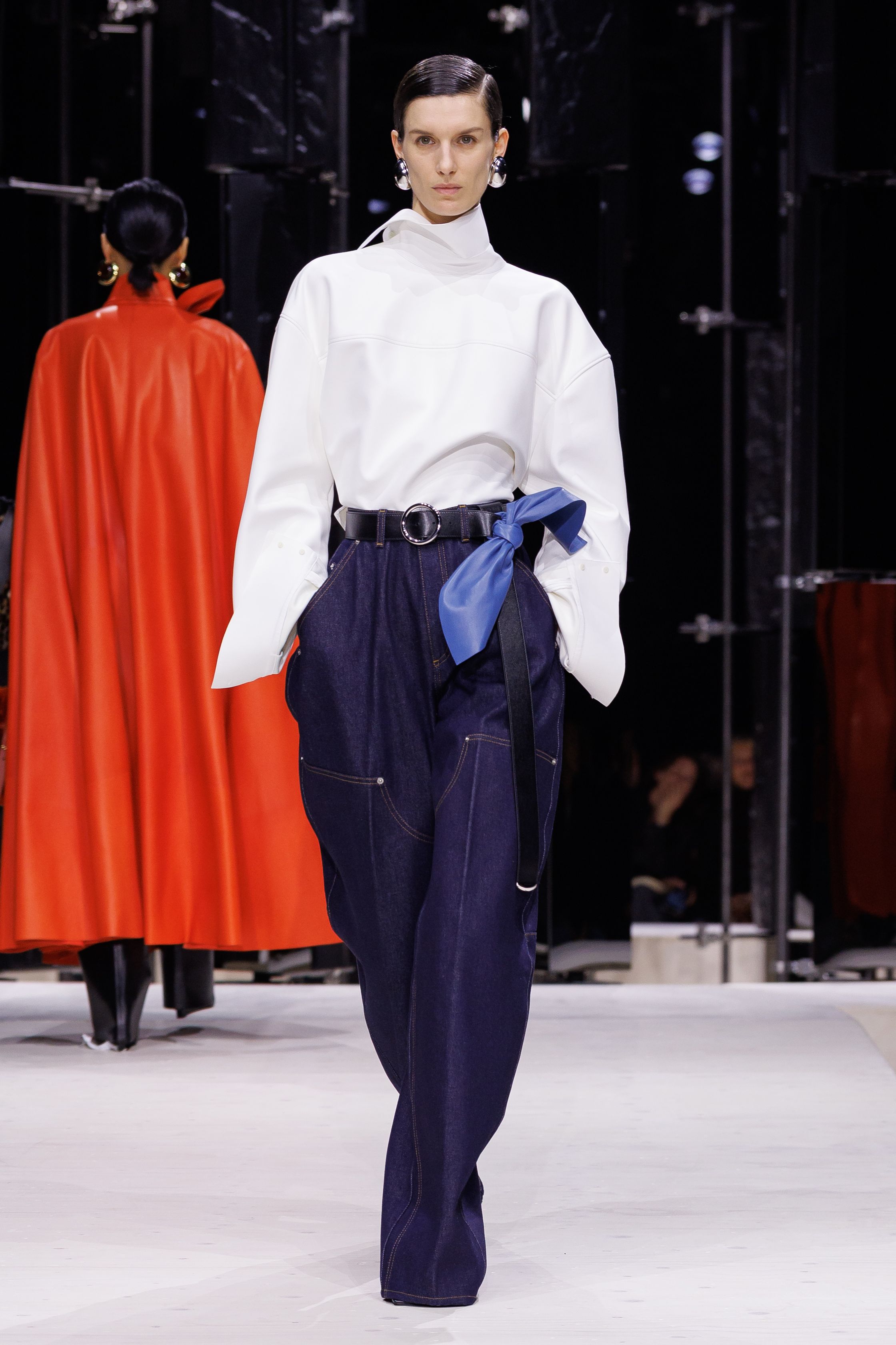 Givenchy 2026秋冬在现代建筑空间中呈现一场充满戏剧性的时装叙事：雕塑式西装、亮色斗篷、结构礼服与夸张装饰共同构建品牌标志性的高级时装气质。蓝色、红色与黄色的高饱和色彩与黑白经典形成鲜明对比，服装通过立体剪裁与夸张廓形展现出强烈视觉张力。整场系列在优雅与戏剧之间取得平衡，展现现代高级时装的力量-顽石频道趋势研究